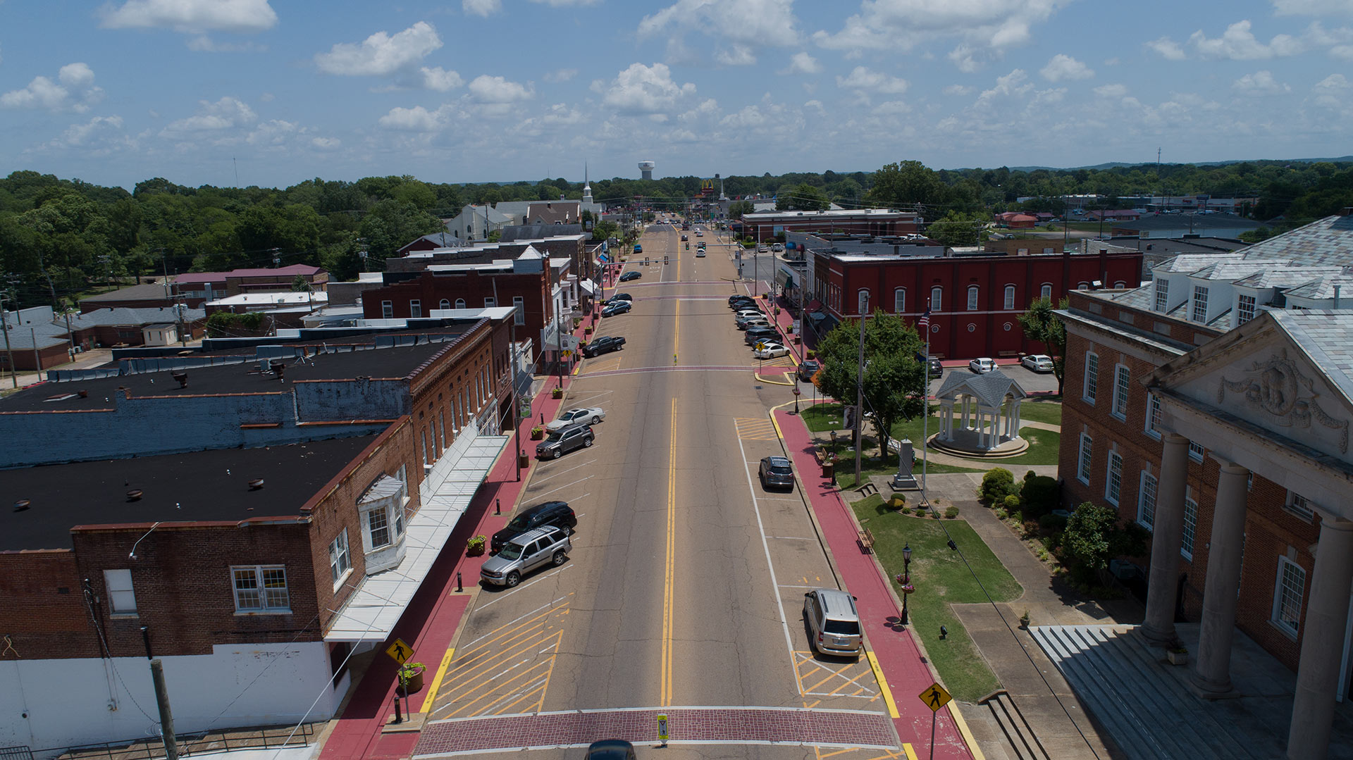An aerial drone view of Hardin County on a beautiful day with the main street in the middle and buildings with cars parked on the streets.